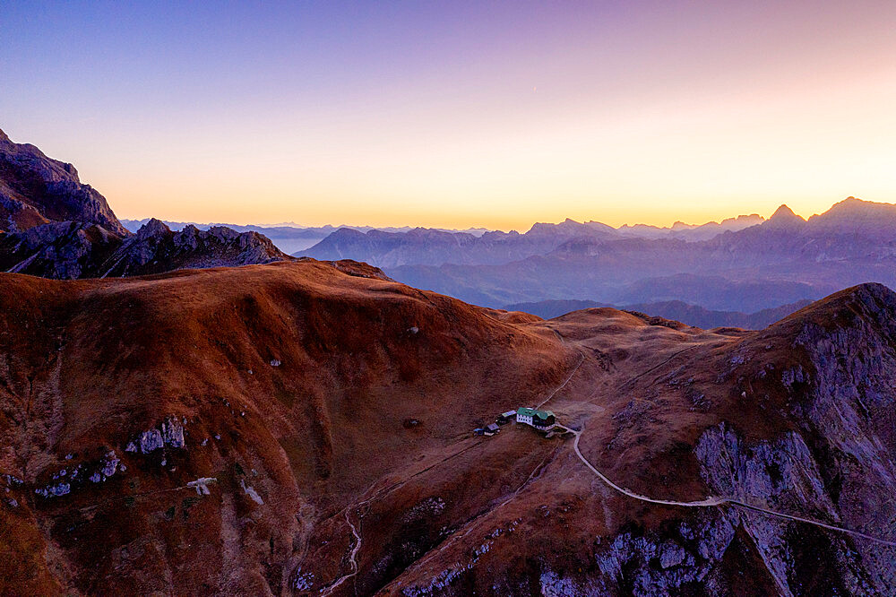 Pink sunrise in autumn over Rifugio Genova hut, aerial view, Col di Poma, Funes Valley, Dolomites, Bolzano, South Tyrol, Italy, Europe