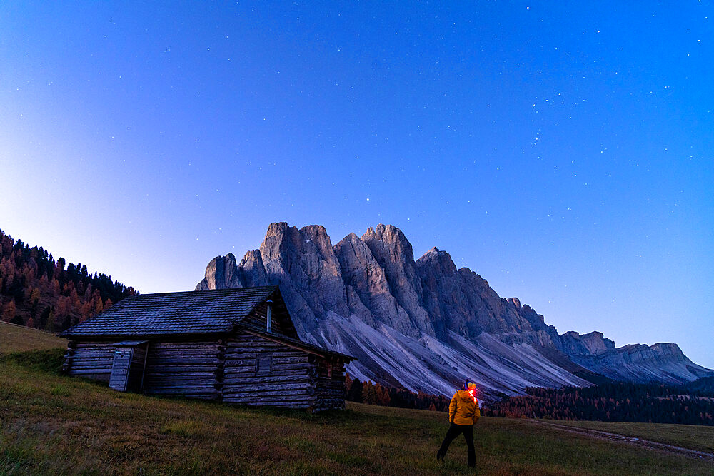 Man admiring stars over the Odle from wooden hut at Gampen Alm, Funes Valley, Dolomites, Bolzano province, South Tyrol, Italy, Europe