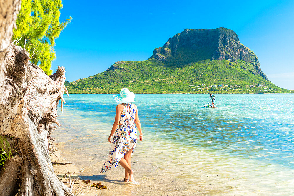 Woman on tropical beach looking at paddleboard in the lagoon, La Gaulette, Le Morne Brabant, Black River, Mauritius, Indian Ocean, Africa