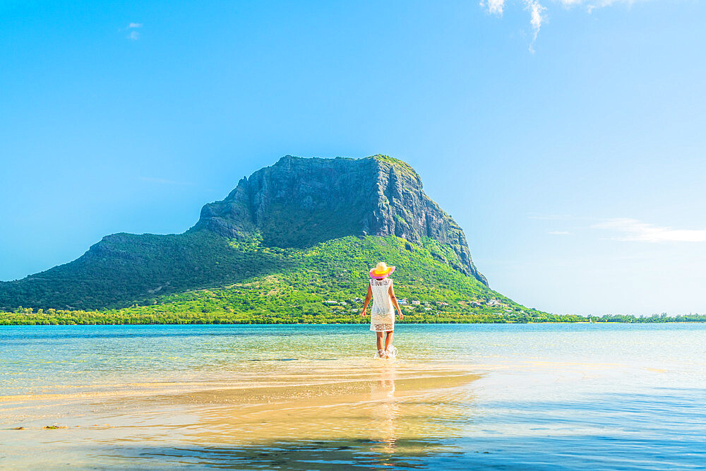 Woman admiring Le Morne mountain standing in the shallow water of turquoise lagoon, La Gaulette, Mauritius, Indian Ocean, Africa