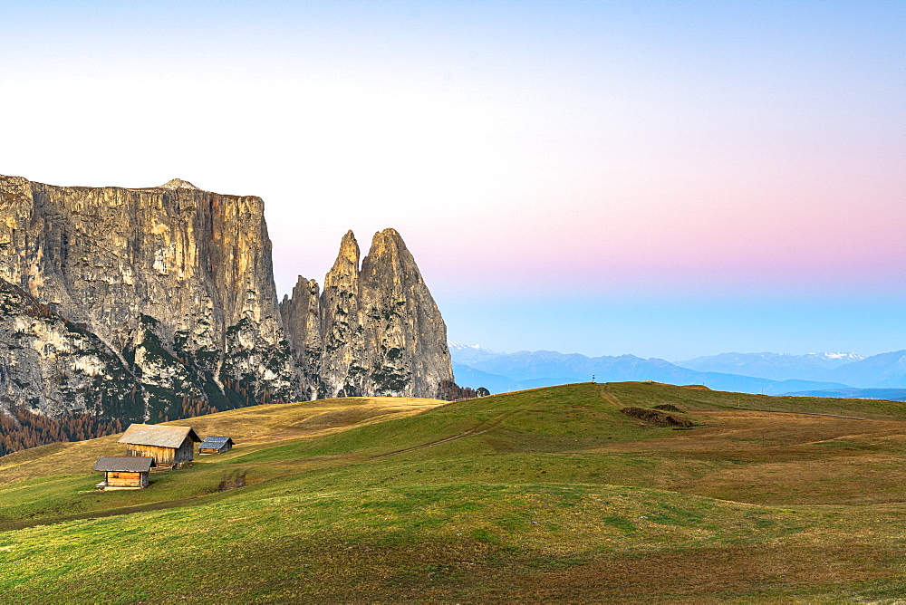 Autumn sunrise over Sciliar peaks and wood huts at Alpe di Siusi (Seiser Alm), Dolomites, South Tyrol, Italy, Europe