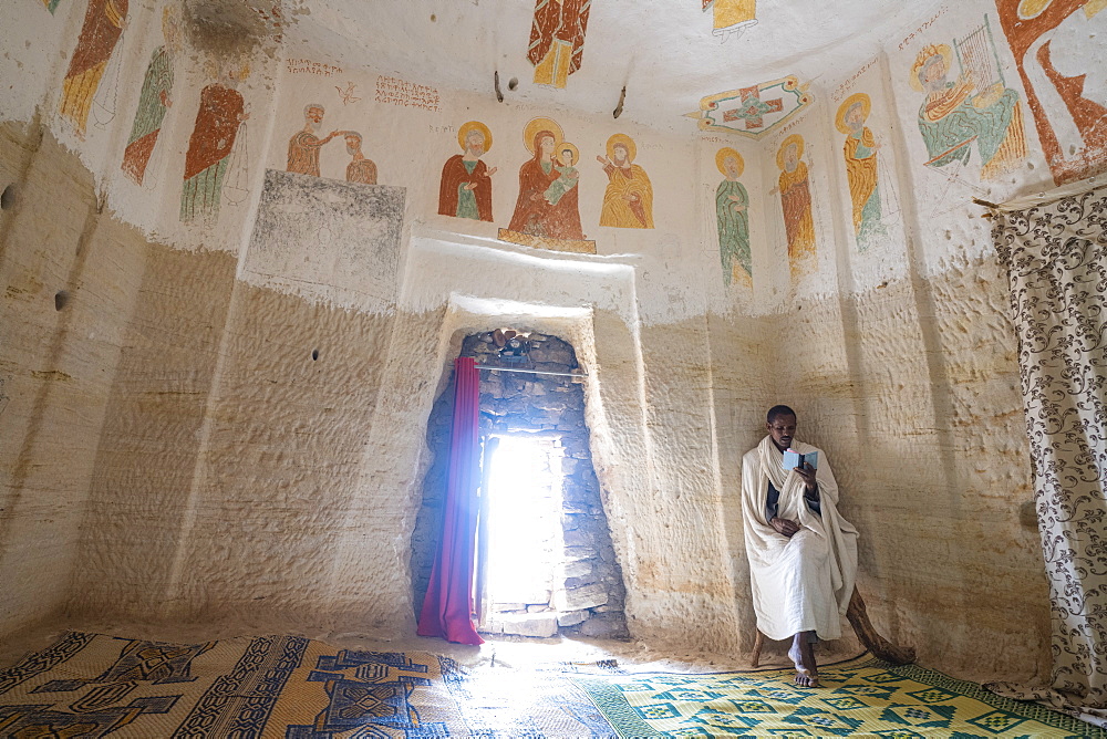 Orthodox Christian priest holding the prayer book inside Daniel Korkor church, Gheralta Mountains, Tigray Region, Ethiopia, Africa