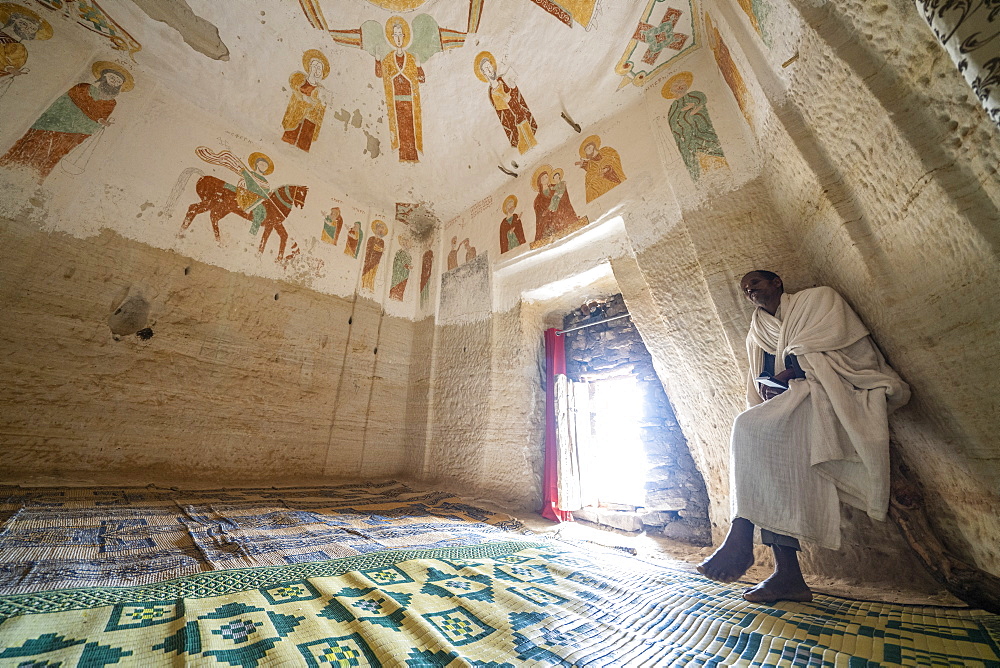 Orthodox priest meditating inside Daniel Korkor rock-hewn church, Gheralta Mountains, Tigray Region, Ethiopia, Africa