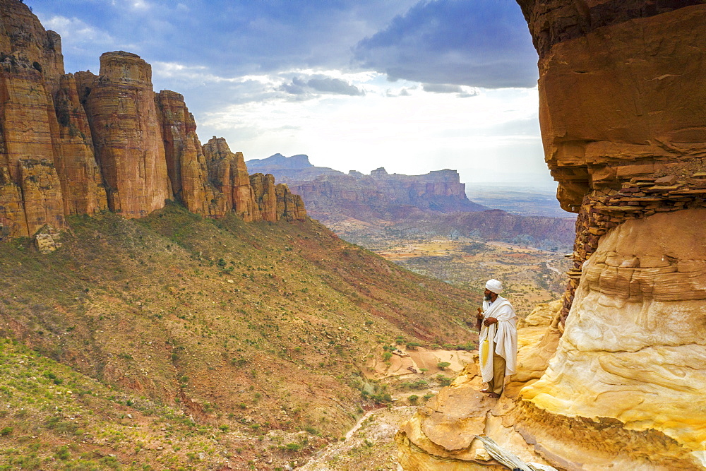 Orthodox priest admiring Gheralta Mountains from the entrance of Abuna Yemata Guh church, Tigray Region, Ethiopia, Africa