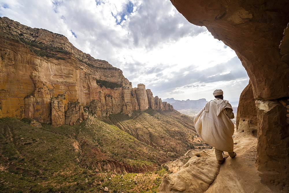 Rear view of priest walking on access trail to the rock-hewn Abuna Yemata Guh church, Gheralta Mountains, Tigray region, Ethiopia, Africa