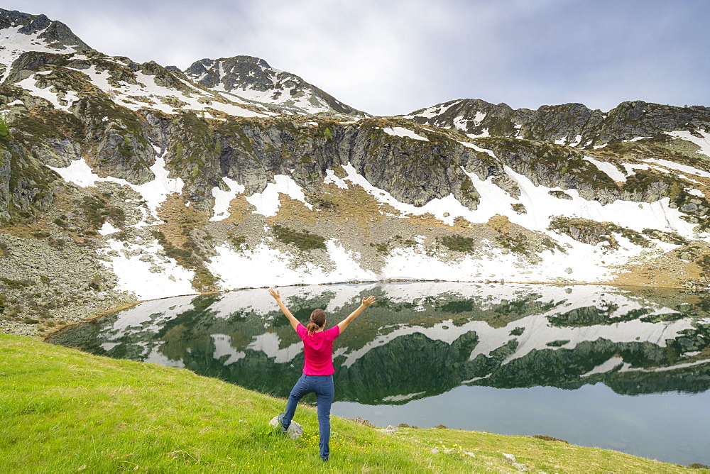 Cheerful woman with outstretched arms standing on the shores of Porcile Lakes, Tartano Valley, Valtellina, Lombardy, Italy, Europe