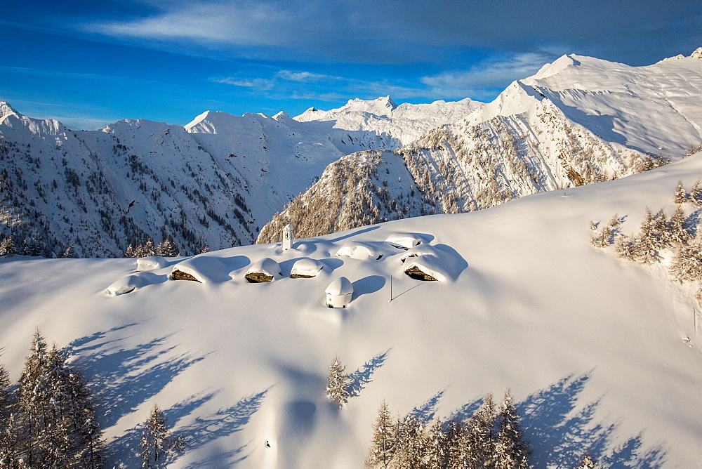 A little village at the foot of Alpe Scima, with its mountain huts and church covered in snow, Valchiavenna, Lombardy, Italy, Europe