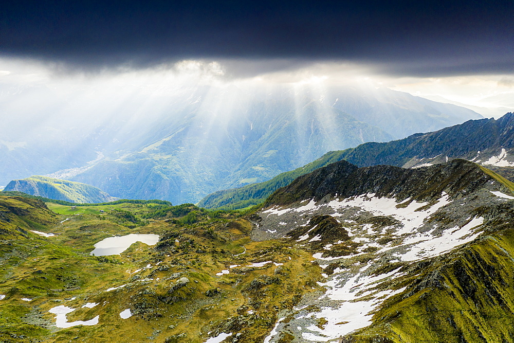 Light beam at sunrise over mountains peaks surrounding Arcoglio lake, Valmalenco, Sondrio province, Valtellina, Lombardy, Italy, Europe