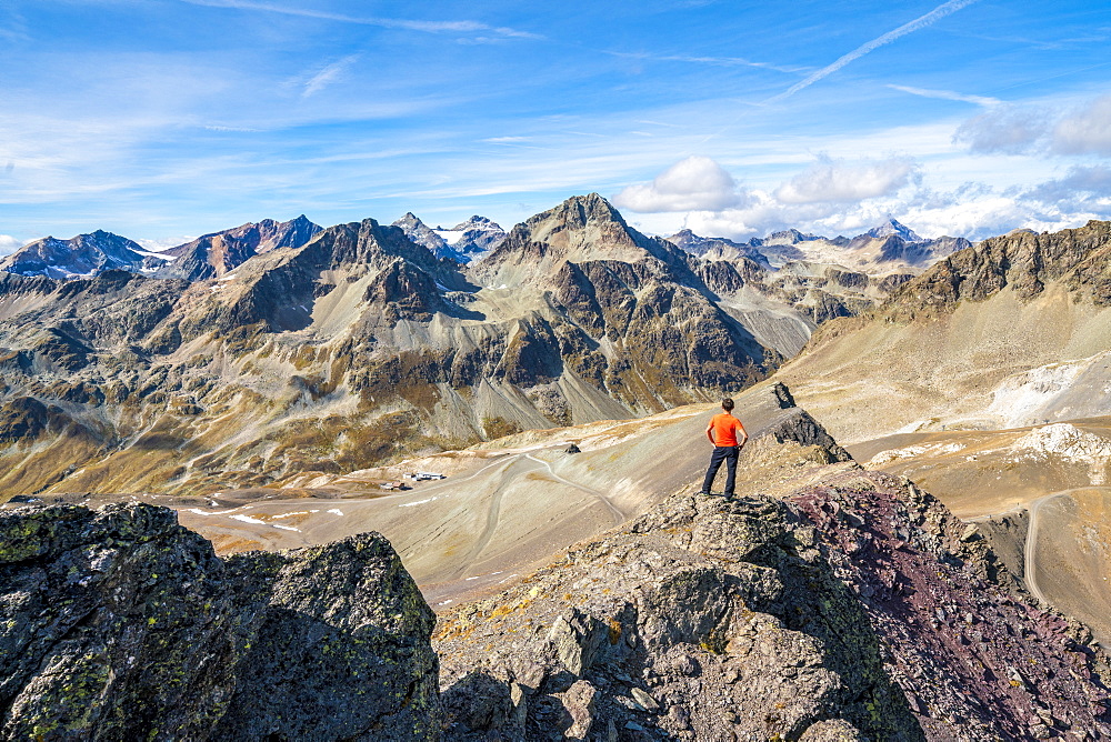 Rear view of man on top of Piz Nair looking towards Piz Suvretta mountain peak, Engadine, canton of Graubunden, Switzerland, Europe