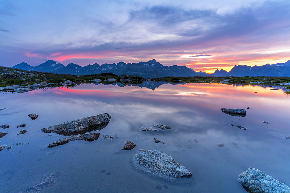 Burning sky at sunset on mountains mirrored in the pristine lake, Muottas Muragl, Engadine, canton of Graubunden, Switzerland, Europe