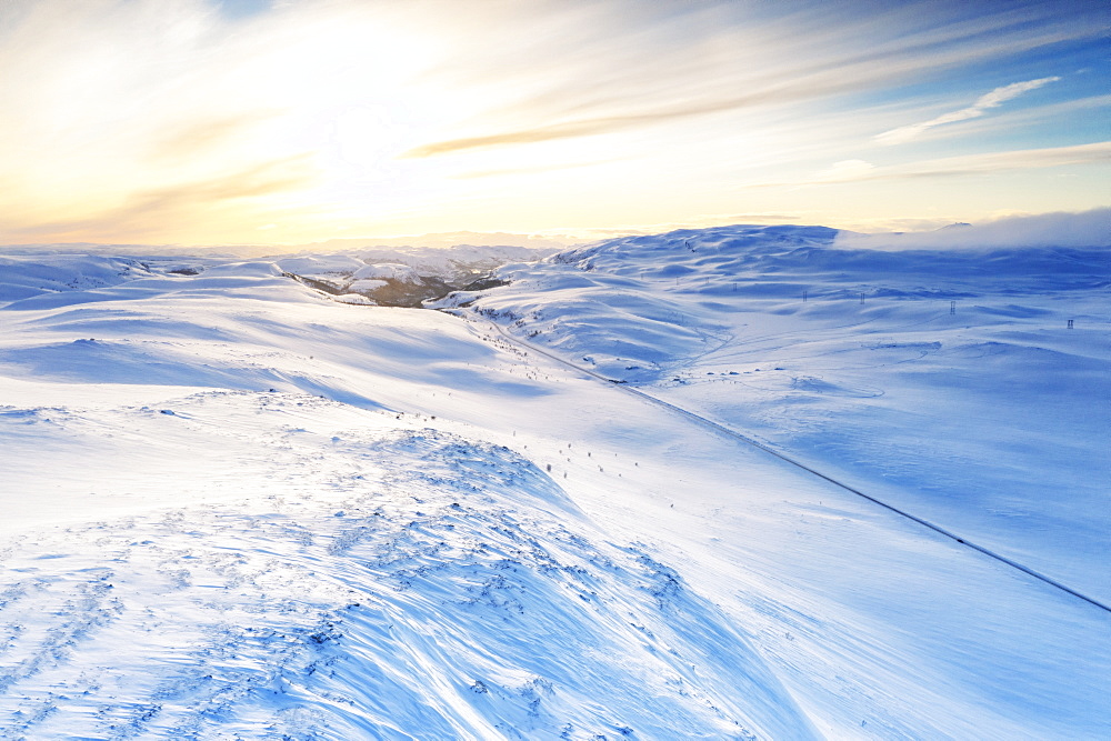 Aerial view of empty road across mountains covered with snow lit by sunrise, Sennalandet, Alta, Troms og Finnmark, Arctic, Norway, Scandinavia, Europe