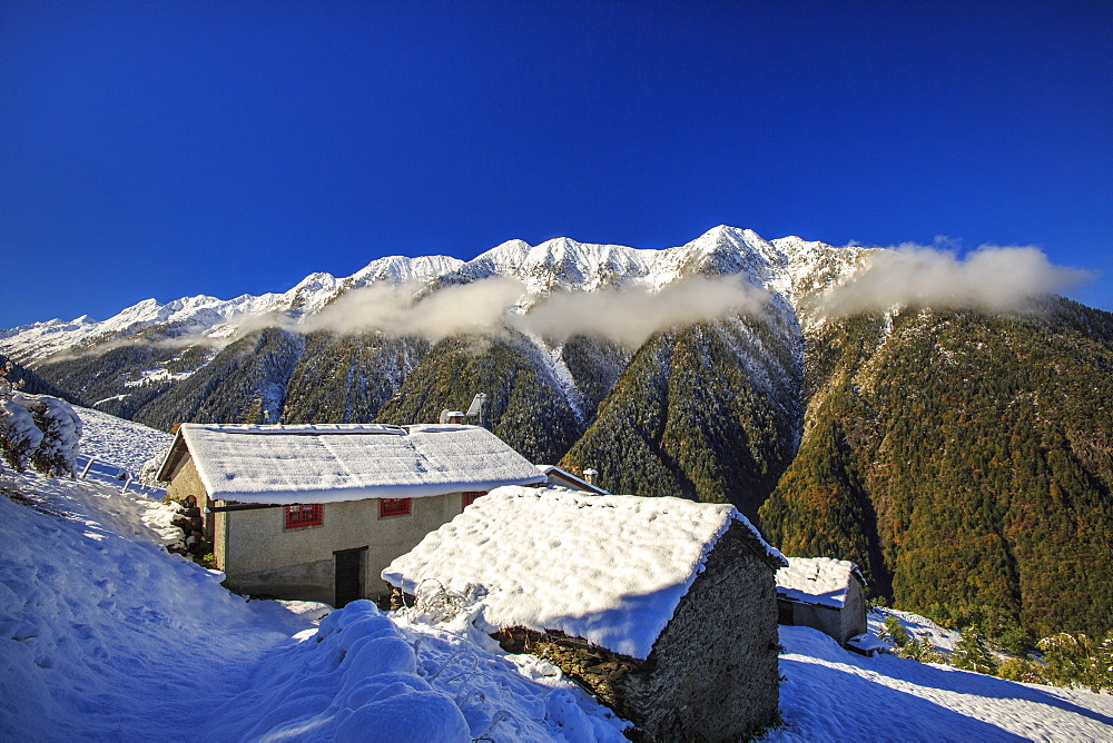 Mountain houses framed by snowy peaks, San Salvatore, Livrio Valley, Orobie Alps, Valtellina, Lombardy, Italy, Europe