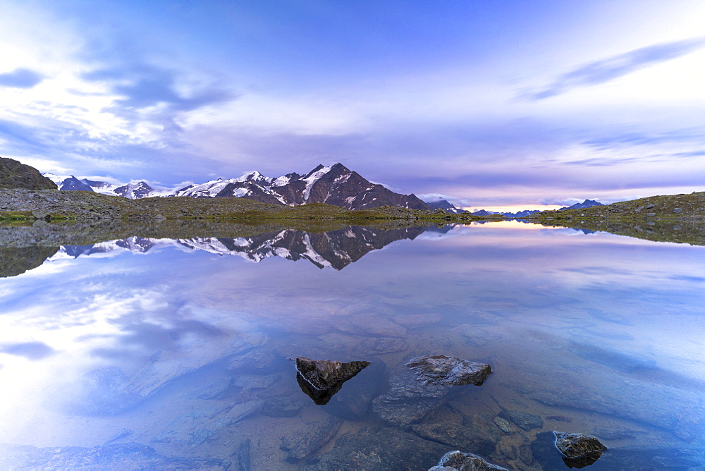 Sunset over the clear water of lake Manzina with Tresero peak on background, Valfurva, Valtellina, Lombardy, Italy, Europe