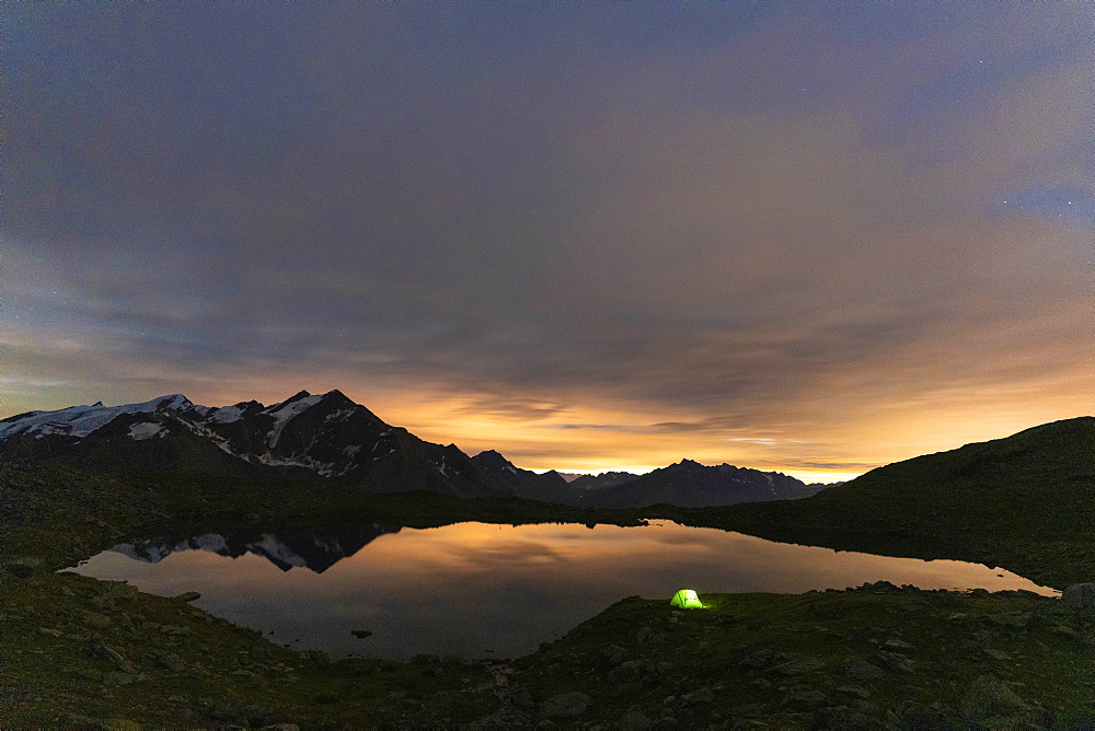 Illuminated tent on shores of lake Manzina at night, aerial view, Valfurva, Valtellina, Sondrio province, Lombardy, Italy, Europe