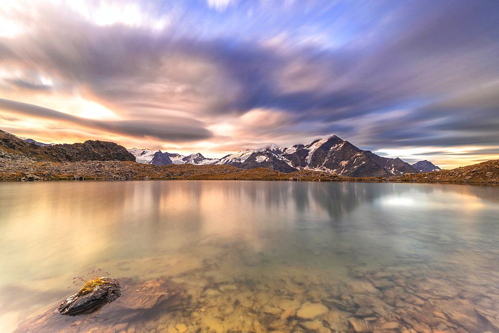 Dramatic sky at sunrise over Tresero peak reflected in lake Manzina, Valfurva, Valtellina, Sondrio province, Lombardy, Italy, Europe