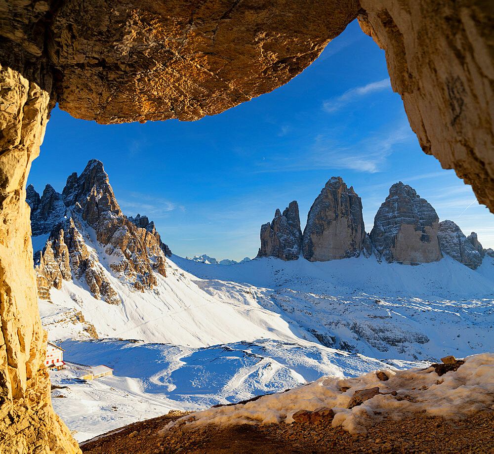 Sunset over the snow capped Tre Cime di Lavaredo and Monte Paterno seen from rock cave, Sesto Dolomites, South Tyrol, Italy, Europe