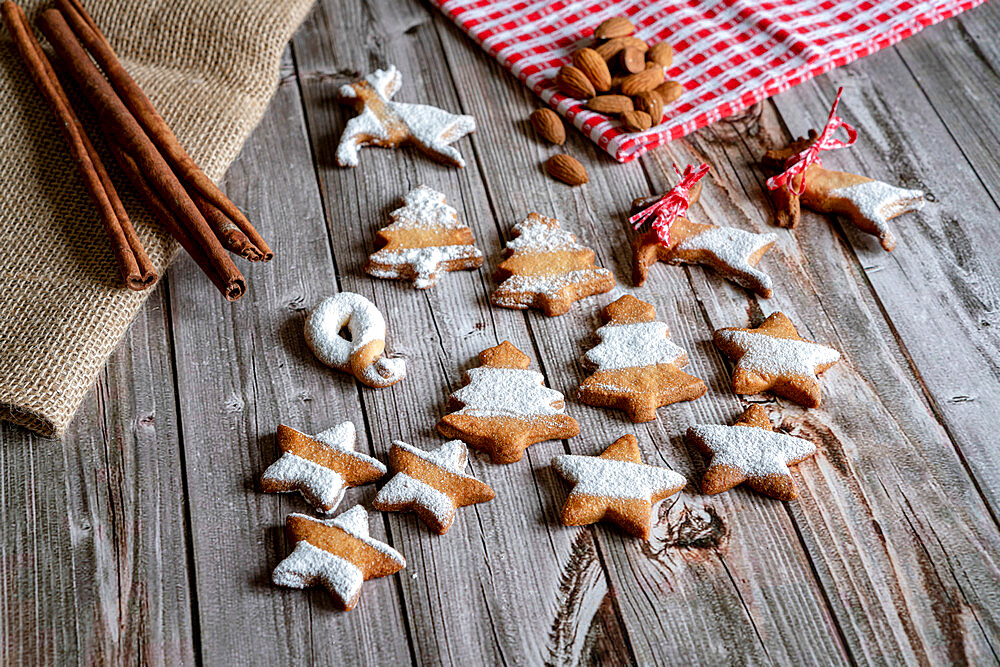 Gingerbread and butter cookies in shape of Christmas tree and stars with almond and cinnamon on wood table background, Italy, Europe