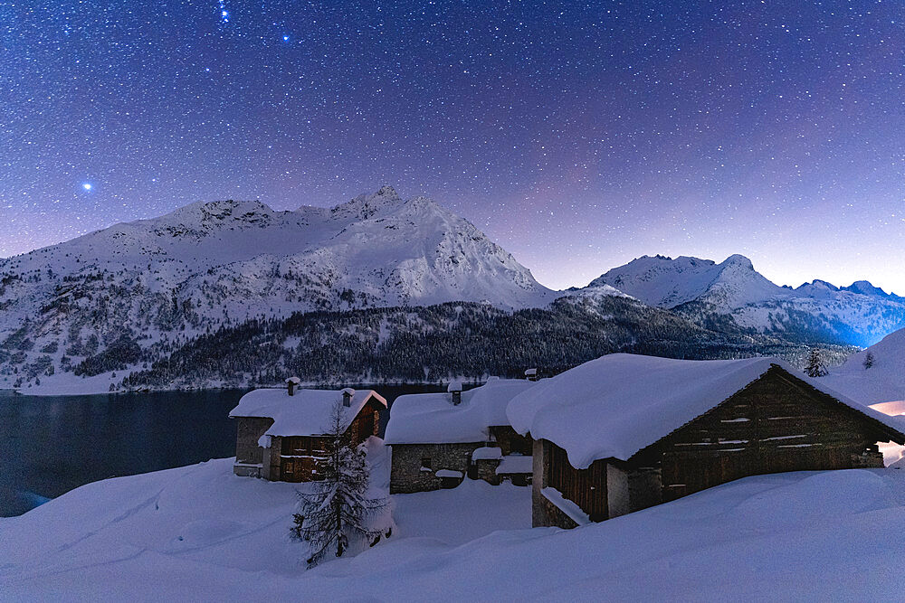 Starry sky over Piz Da La Margna peak and Spluga huts covered with snow, Maloja, Engadine, canton of Graubunden, Switzerland, Europe