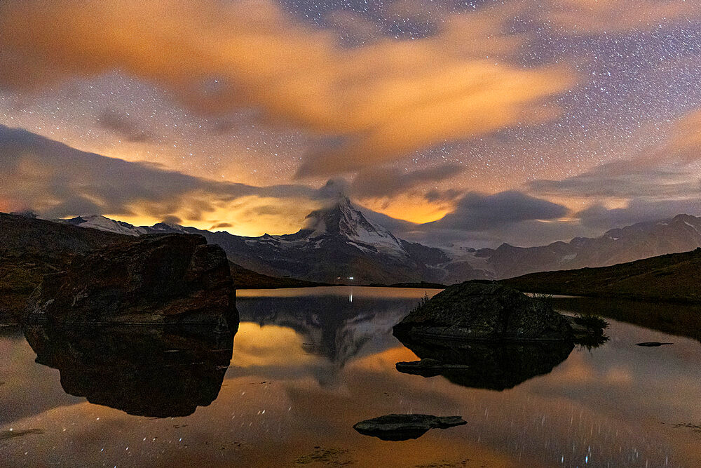 Clouds in the starry sky above Matterhorn reflected in lake Stellisee, Zermatt, Valais canton, Switzerland, Europe