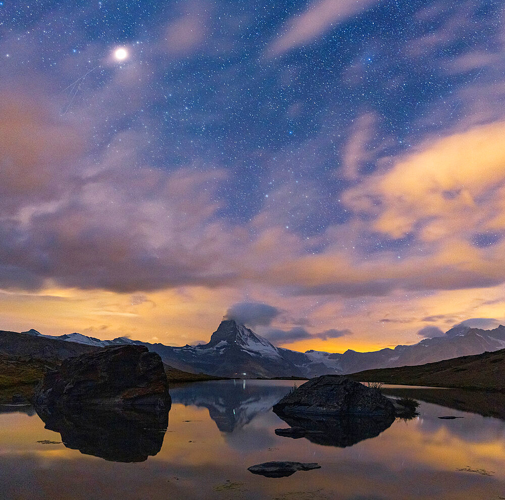 Matterhorn peak lit by moon in the starry night sky viewed from Stellisee, Zermatt, Valais canton, Switzerland, Europe