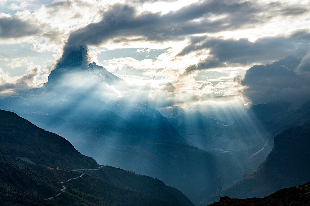 Sun rays through clouds over Matterhorn during a backlit sunset, Zermatt, Valais canton, Switzerland, Europe