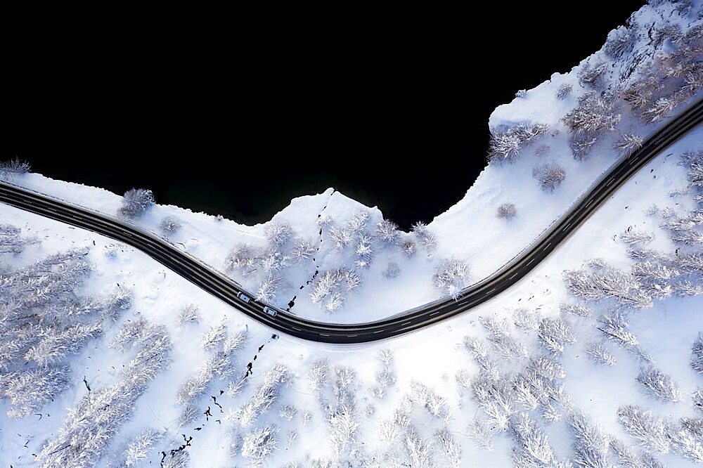 Cars traveling on snowy road on shore of Lake Sils from above, Engadine, Graubunden Canton, Switzerland, Europe