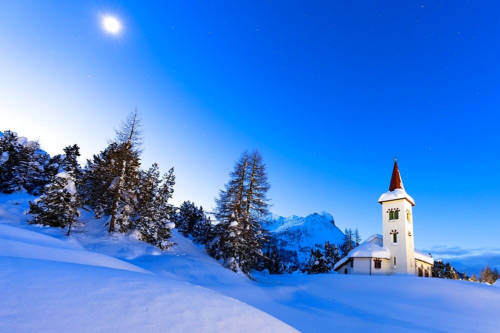 Dusk over Chiesa Bianca in the snowy landscape lit by moon, Maloja, Bregaglia Valley, Engadine, Graubunden Canton, Switzerland, Europe