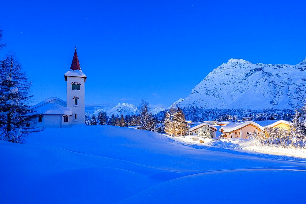 Alpine village of Maloja and Chiesa Bianca covered with snow at dusk, Bregaglia, Engadine, Graubunden Canton, Switzerland, Europe