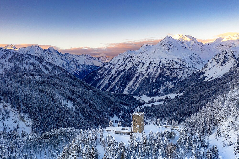 Sunrise on ancient Torre Del Belvedere tower and snowy woods, Maloja, Bregaglia, Engadine, Graubunden Canton, Switzerland, Europe