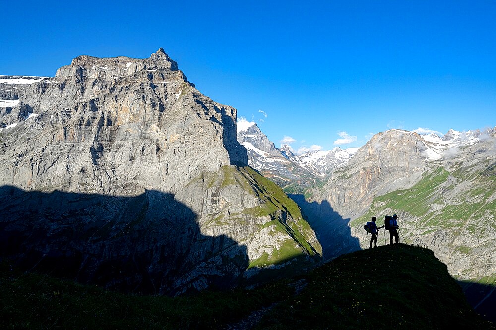 Two hikers admiring mountains during the hike towards Muttsee Hut on Kalktrittli path, Canton of Glarus, Switzerland, Europe