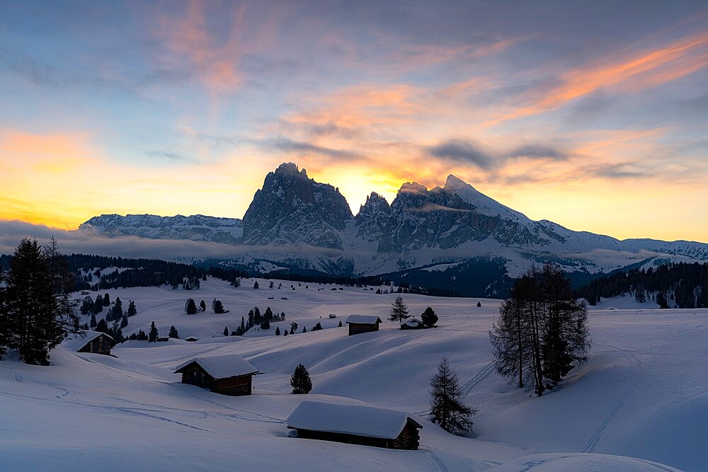 Mountain huts covered with snow with Sassopiatto and Sassolungo in background at dawn, Seiser Alm, Dolomites, South Tyrol, Italy, Europe