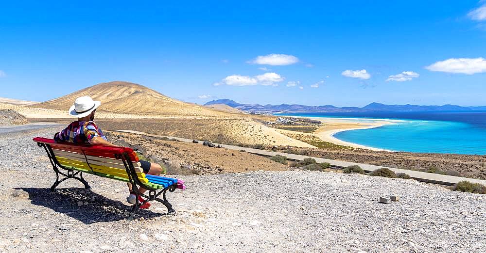 Tourist admiring the crystal ocean from a bench at Mirador Del Salmo viewpoint, Costa Calma, Fuerteventura, Canary Islands, Spain, Atlantic, Europe