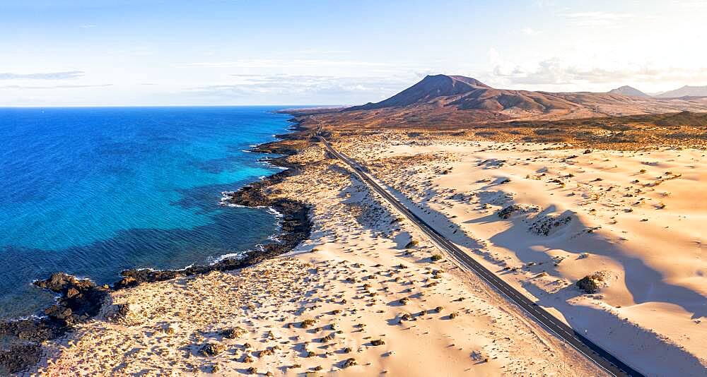 Empty road crossing the sand dunes overlooking the ocean, Corralejo Natural Park, Fuerteventura, Canary Islands, Spain, Atlantic, Europe