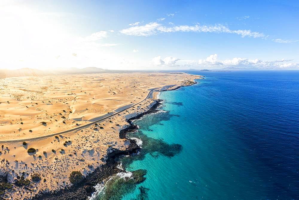 Aerial view of empty road beside the crystal turquoise ocean and sand dunes, Corralejo, Fuerteventura, Canary Islands, Spain, Atlantic, Europe