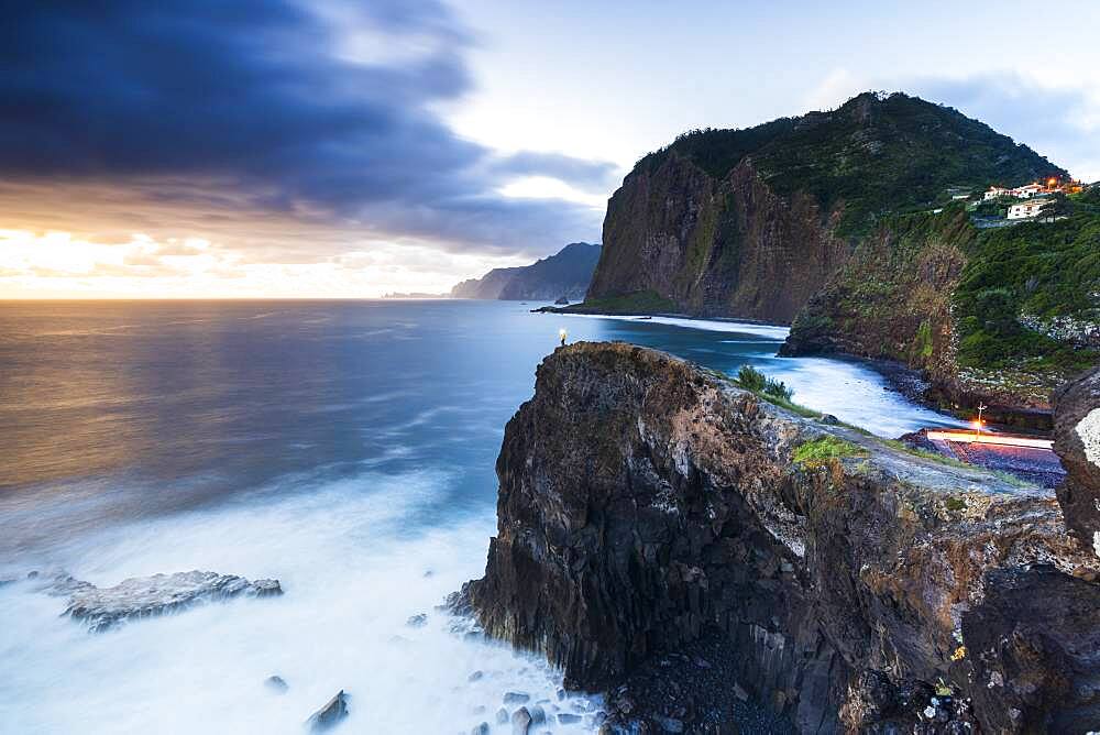 Hiker with head torch admiring the blue hour from cliffs at Miradouro Do Guindaste viewpoint, Madeira island, Portugal, Atlantic, Europe