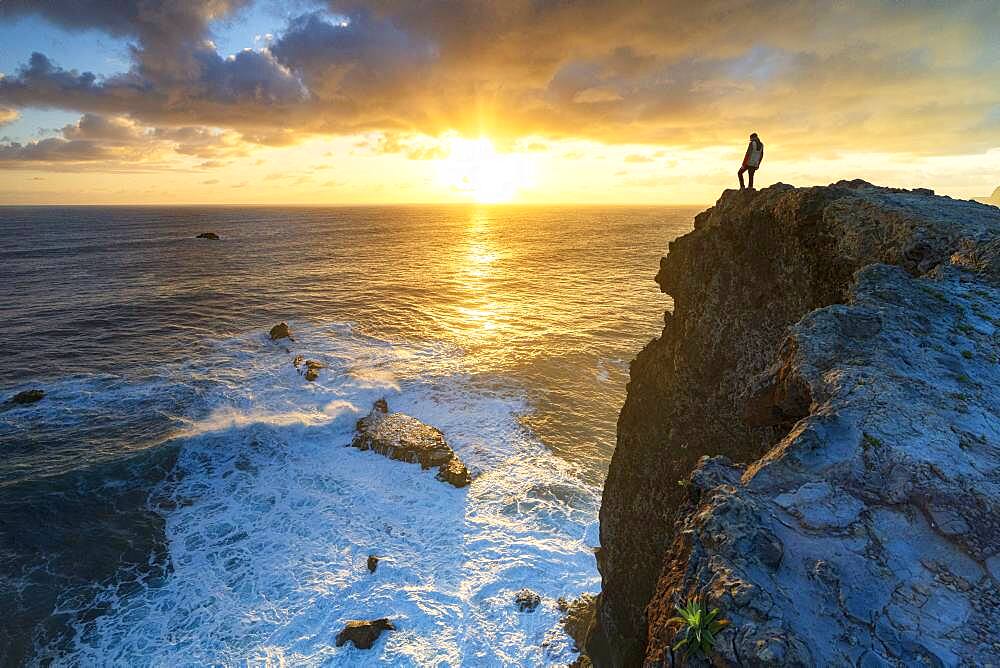 One man watching sunrise over the ocean waves from cliffs, Madeira island, Portugal, Atlantic, Europe