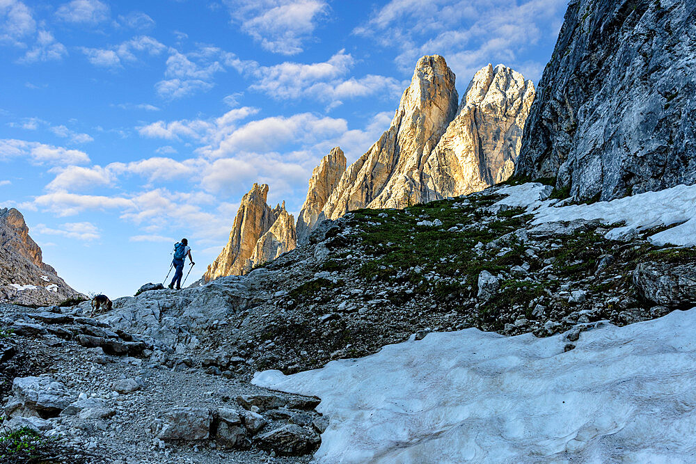 Hiker woman walking on path to majestic Croda Dei Toni mountain at dawn, Val Fiscalina, Sesto Dolomites, South Tyrol, Italy, Europe