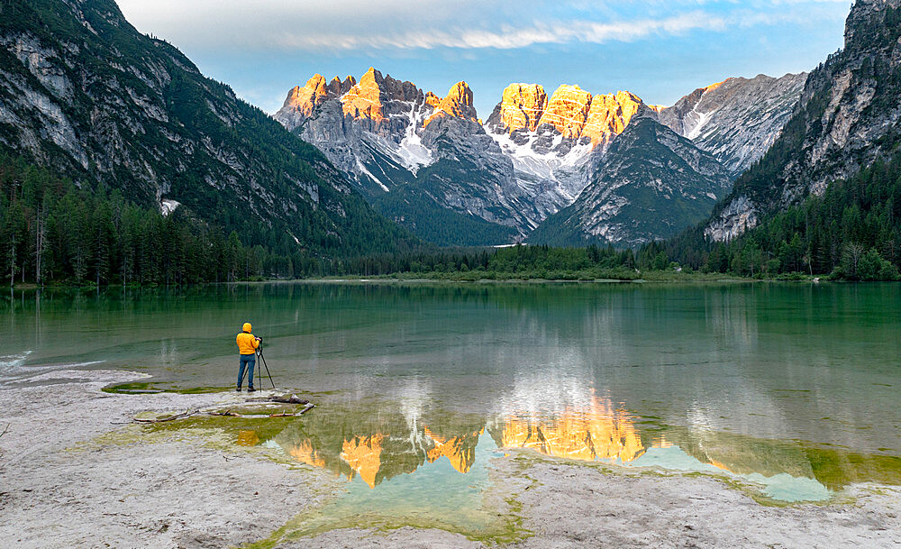 Photographer with tripod admiring the Dolomites at dawn from lake Landro, Dolomites, Bolzano province, South Tyrol, Italy, Europe