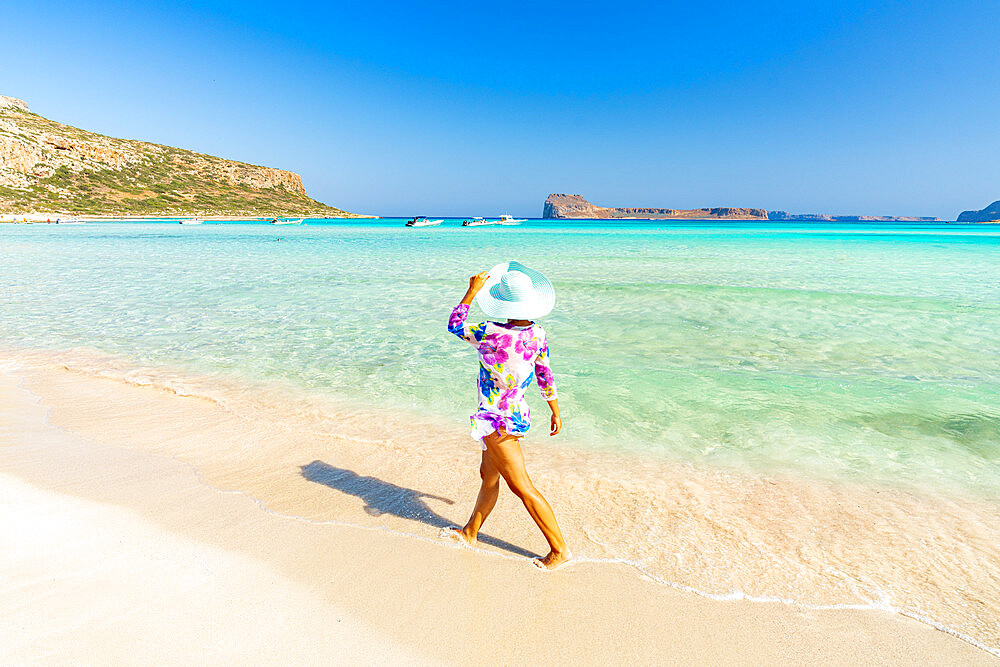 Beautiful woman with sun hat walking on idyllic empty beach, Crete, Greek Islands, Greece, Europe