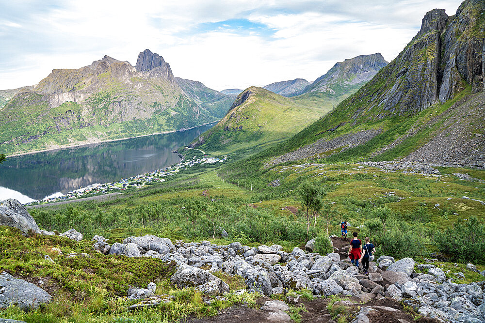 Hikers approaching the climbing path to Hesten Mountain peak from hills nearby Fjordgard, Senja, Troms county, Norway, Scandinavia, Europe