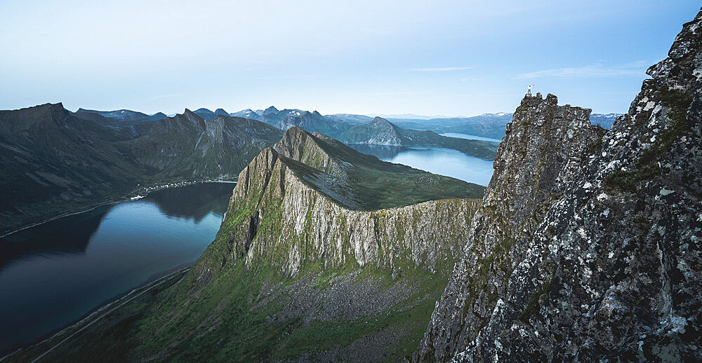 Hiker looking at the fjord at dusk from top of Husfjellet mountain, Senja island, Troms county, Norway, Scandinavia, Europe