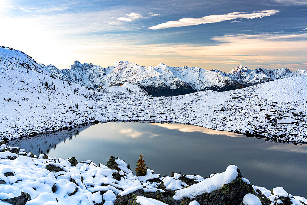 Mountain peaks of Orobie Alps covered with snow reflecting in the frozen Rogneda lake at dawn, Rhaetian Alps, Lombardy, Italy, Europe