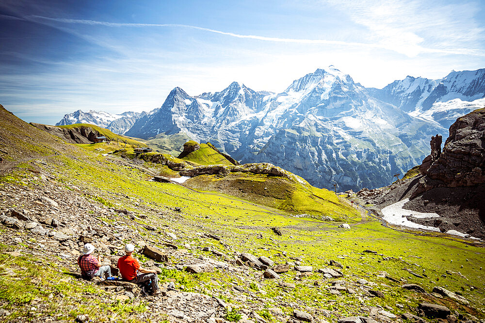 Two people admiring Eiger, Monch and Jungfrau mountains from meadows, Murren Birg, Jungfrau Region, Bern Canton, Swiss Alps, Switzerland, Europe