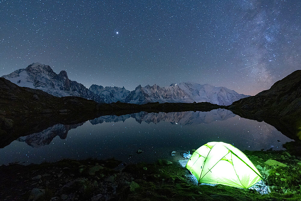 Illuminated tent under the stars at Lacs des Cheserys with Mont Blanc massif reflected in water, Chamonix, Haute Savoie, French Alps, France, Europe