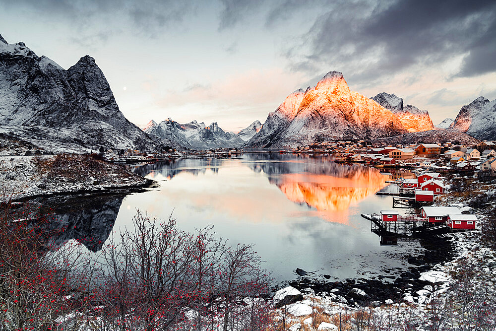 Clouds at dawn over traditional Rorbu and Olstind mountain reflected in sea, Reine Bay, Nordland, Lofoten Islands, Norway, Scandinavia, Europe