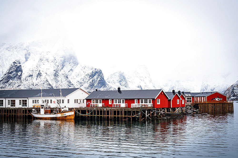 Foggy sky over snowcapped mountains and traditional Rorbu cabins by the sea, Hamnoy, Nordland county, Lofoten Islands, Norway, Scandinavia, Europe