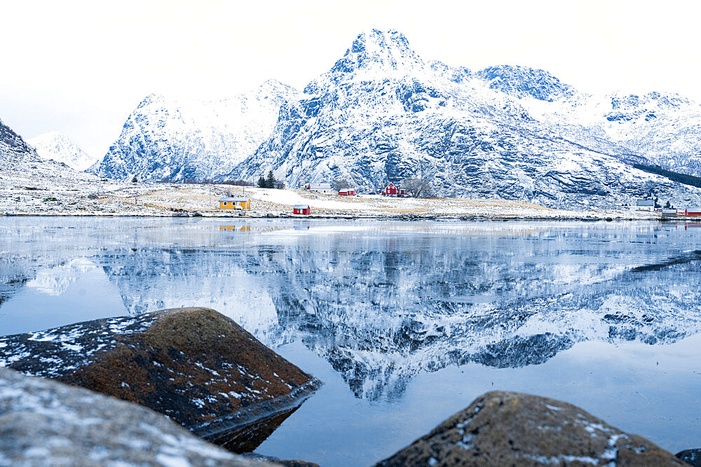 Majestic mountain peaks mirrored in the icy sea in winter, Flakstadpollen, Flakstadoya, Nordland, Lofoten Islands, Norway, Scandinavia, Europe