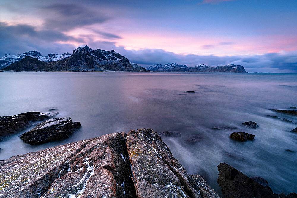 Pink Arctic sunrise over snowcapped mountains and frozen fjord, Vareid, Flakstad, Nordland county, Lofoten Islands, Norway, Scandinavia, Europe