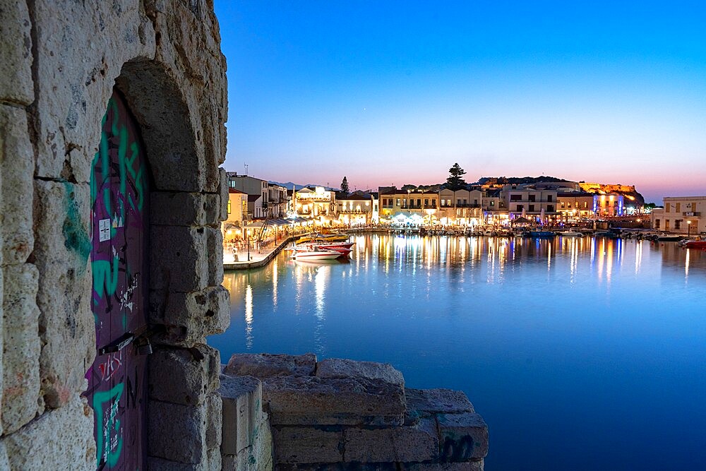 Lights of old Venetian port reflected in the sea at dusk, Rethymno, Crete island, Greek Islands, Greece, Europe