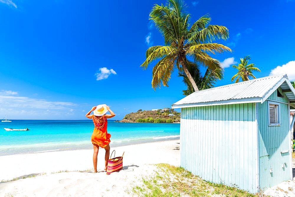 Beautiful woman with straw hat and dress relaxing on tropical beach, Antigua, Leeward Islands, Caribbean, West Indies